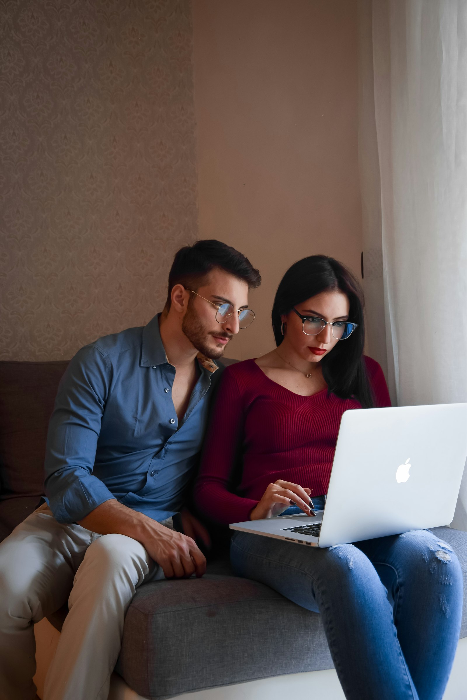 Couple sitting close together on a couch with a laptop